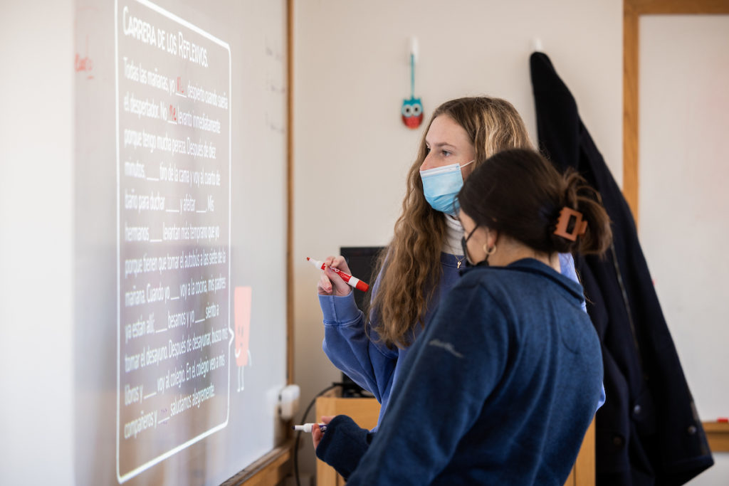 Two female students do a vocabulary exercise at the whiteboard during a Spanish class at Tilton School.