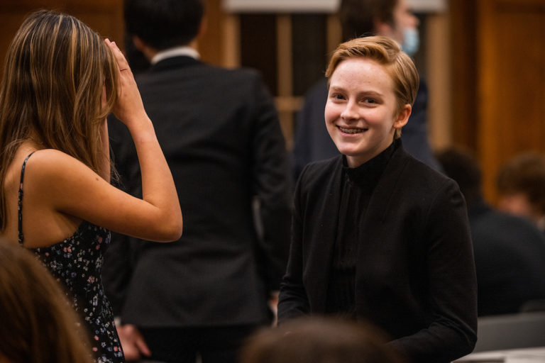 A Tilton student wearing formal attire smiles during a school dinner.